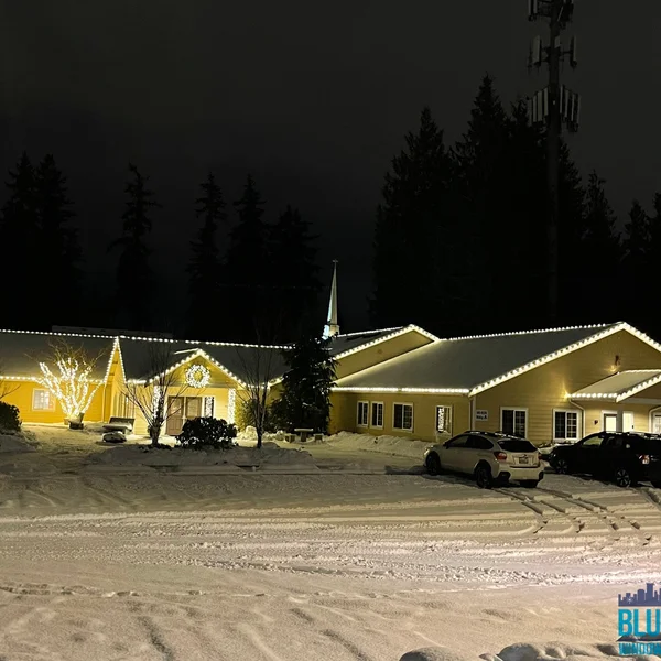 Commercial building illuminated with holiday lights by professional exterior maintenance service in snowy conditions.