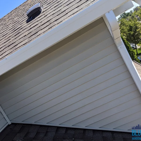 Clean, white gutters and siding showcase residential moss and algae removal work.