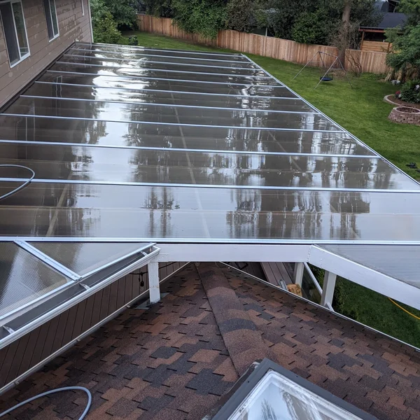 Residential roof with cleaned translucent patio cover shines, thanks to soft wash roof cleaning services.