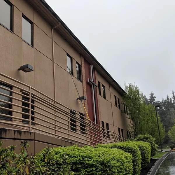 Commercial building's exterior being soft washed by a pressure washer in this gutter cleaning service.