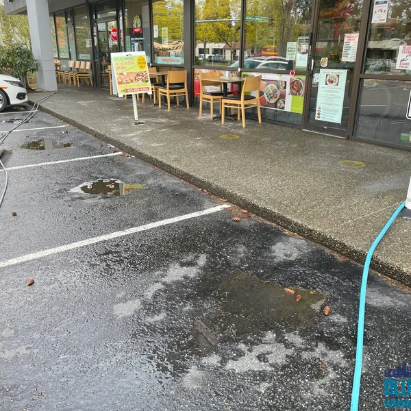 Dirty commercial parking lot with puddles needs surface cleaning and pressure washing services.