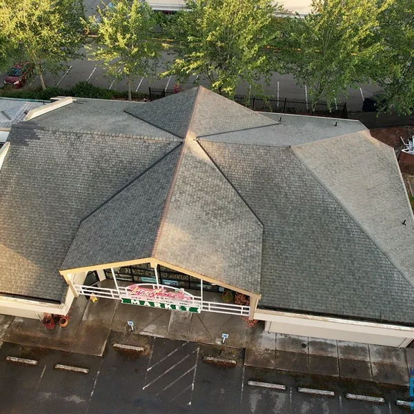 Aerial view of a commercial gray shingle roof before cleaning and pressure washing services are performed.