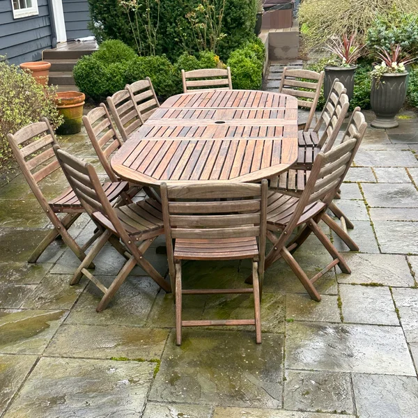 Weathered wood dining set on patio shows need for professional wood restoration services.