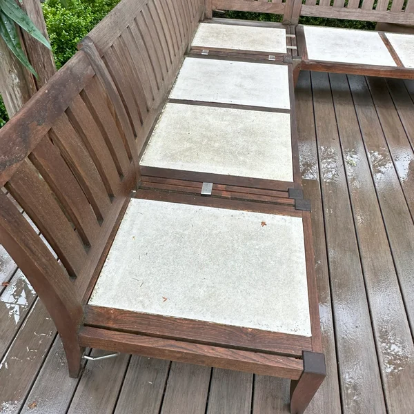 Weathered wood bench with concrete inserts on a deck, prior to professional cleaning and restoration.