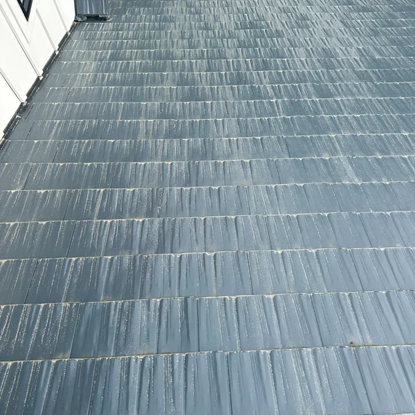 Gray residential roof undergoing soft wash cleaning to remove algae and stains.