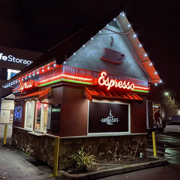 Aroma Cafe building features newly installed commercial lights, including red neon signs and white string lights along the
