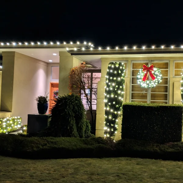 Home exterior adorned with professionally installed warm white Christmas lights and a festive wreath.