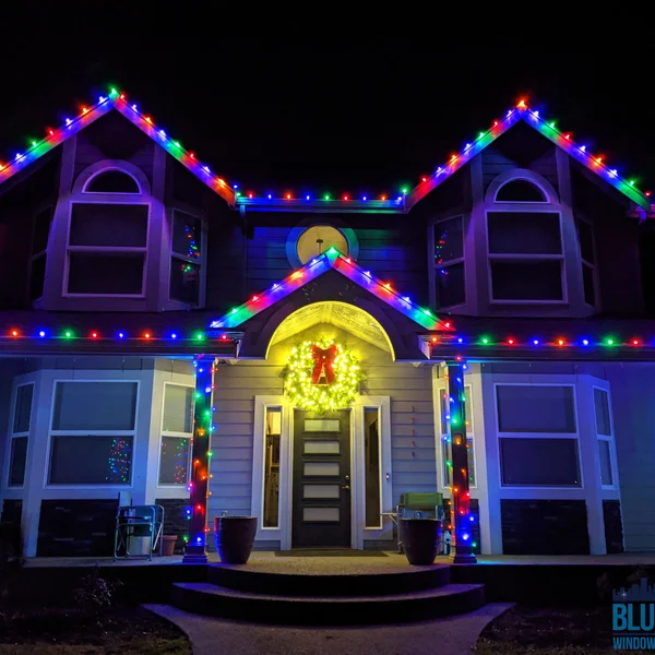 Residential house with Christmas lights professionally installed on the roofline and columns.