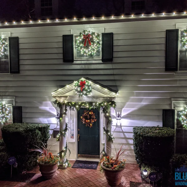 Residential house is decorated for Christmas with wreaths, lights, and garland as part of exterior cleaning service.