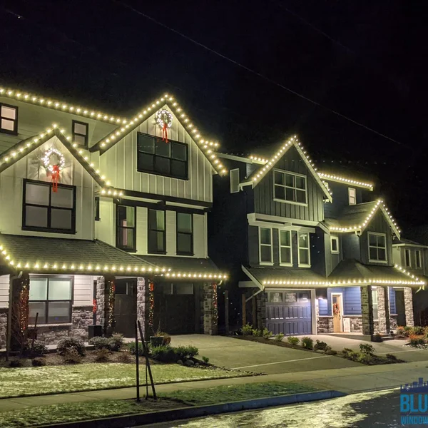 Residential homes glow with professionally installed Christmas lights and wreaths in the dark.