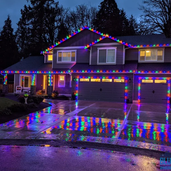 Residential house is decorated with colorful Christmas lights on its roof and garage outlining.