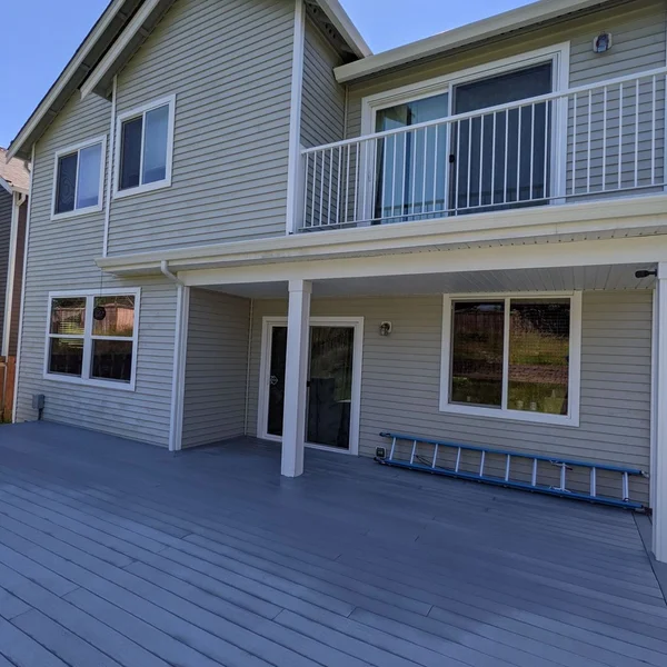 Residential exterior soft wash cleaning shows a clean house with a blue ladder and grey deck.