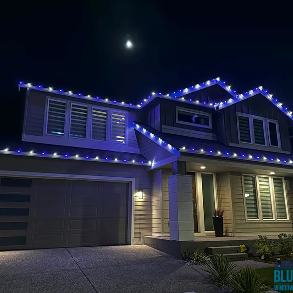Residential home with festive blue Christmas lights professionally installed by our exterior maintenance team.