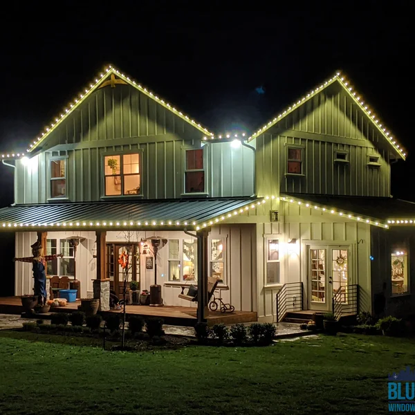 Residential home exterior featuring custom Christmas lights on gutters and roofline at night.