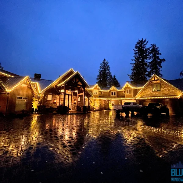 Large home has a soft wash roof cleaning and holiday lights installed on the brown roof line during the evening.