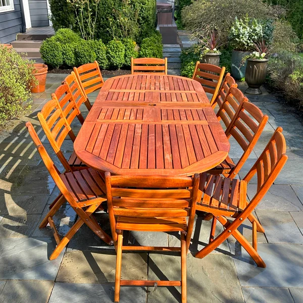 Restored wood dining set shines on patio; residential wood restoration by exterior maintenance company.