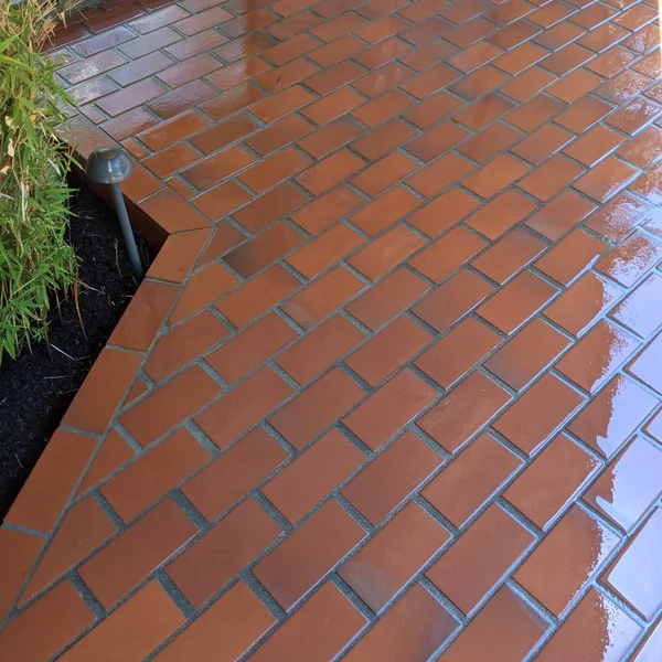 Clean red brick commercial walkway glistens after professional pressure washing and surface cleaning.