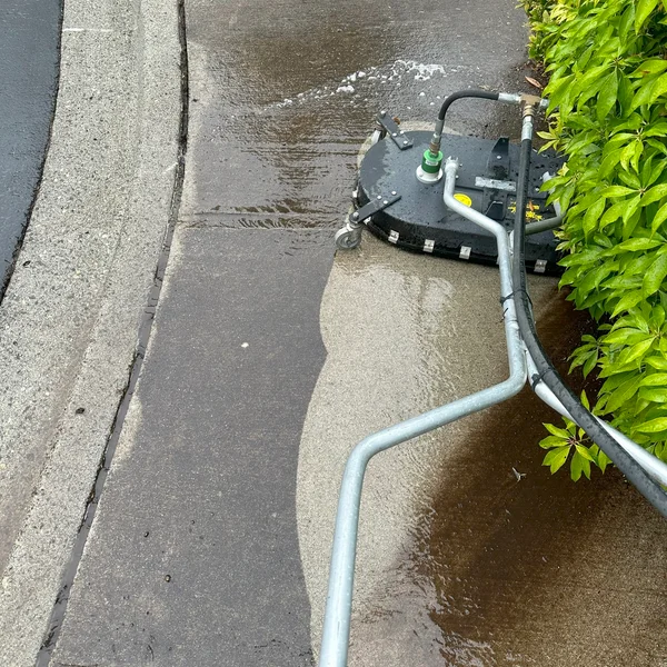 Surface cleaner pressure washing concrete sidewalk, half clean, for exterior maintenance services.