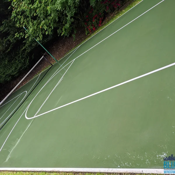 Residential tennis court shows algae removal using soft wash by professional exterior cleaning company.