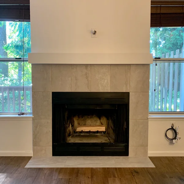 Newly tiled fireplace with a white mantel is flanked by windows for a Greater Seattle home renovation.
