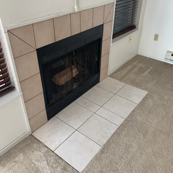 A fireplace with dated tile is ready for a Seattle home renovation to modernize the living space.