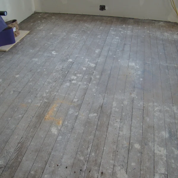 Worn gray hardwood floors needing refinishing are shown during a Seattle home renovation project.