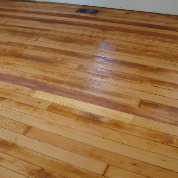 Damaged light brown hardwood flooring with dark stains requires expert Seattle home renovation.