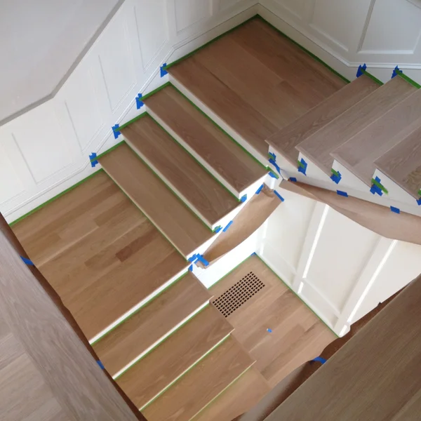 Wooden stairs with blue tape are being prepared for refinishing during home renovation in Seattle.