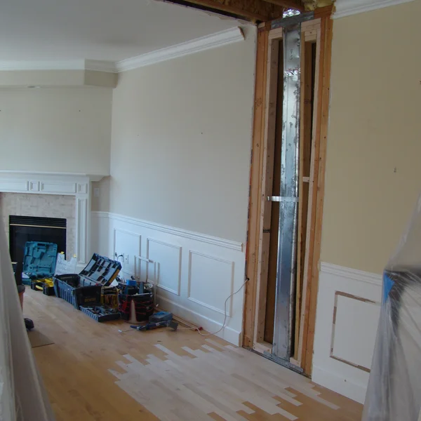 Interior view during a Seattle home renovation project, showing wall framing, fireplace, and tools on light hardwood