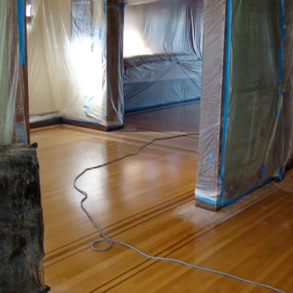 Seattle home renovation: Refinished wood floors gleam under plastic sheeting during a renovation project.