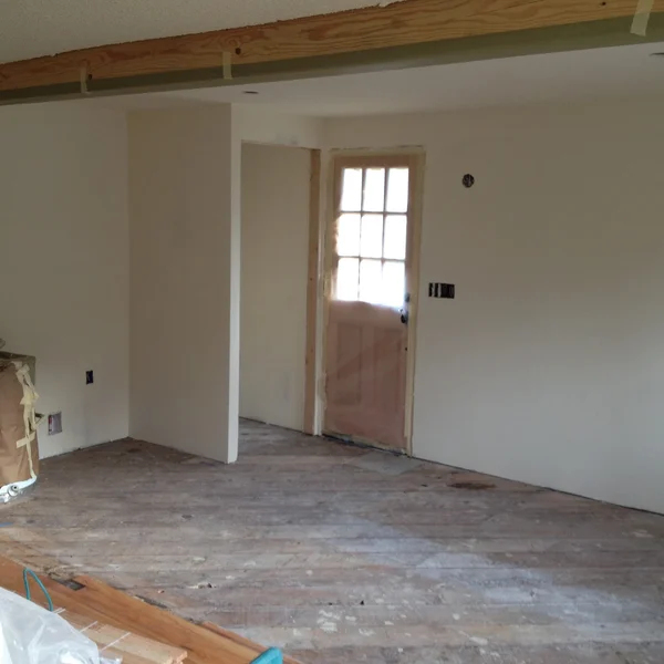 Seattle kitchen remodel shows pre-renovation bare wood floors and a paneled exterior door with white walls.
