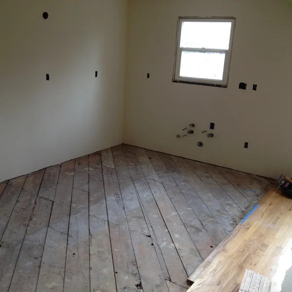 Seattle kitchen renovation shows wood flooring and wall preparations prior to remodeling project.