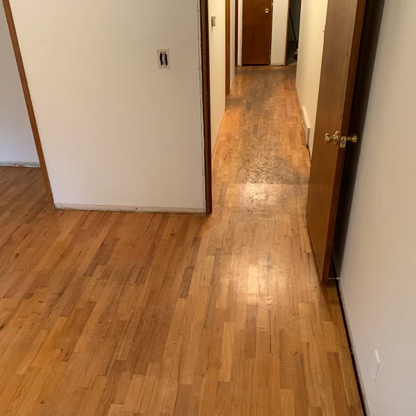 A hallway with hardwood floors showing signs of wear, part of a home renovation project in Seattle.