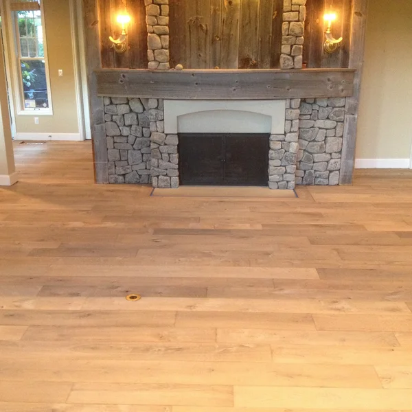 Light wood floors and a stone fireplace with wood accents create a cozy and rustic look in this Seattle home renovation.