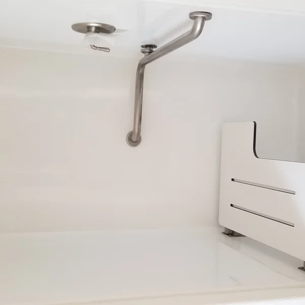 Interior of a white manufactured home shower stall featuring safety grab bars and a shower seat.