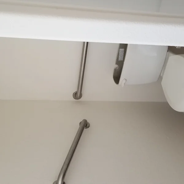 Accessibility features in the ADU bathroom include a toilet and metal grab bars for safety and support.