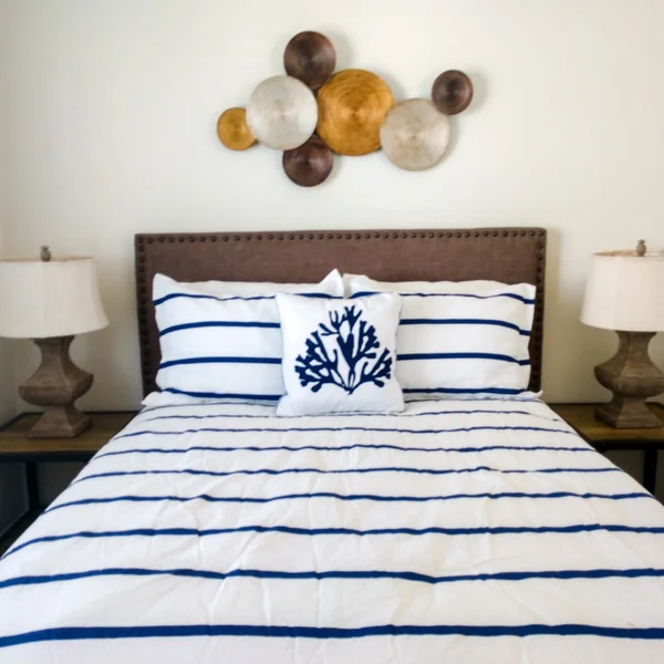 A bedroom in an ADU features a queen bed with blue striped bedding and nautical themed decor.