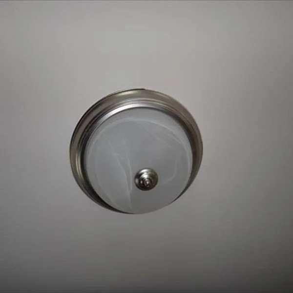 The modern ceiling light fixture with nickel trim and a decorative glass cover illuminates this manufactured home's interior.