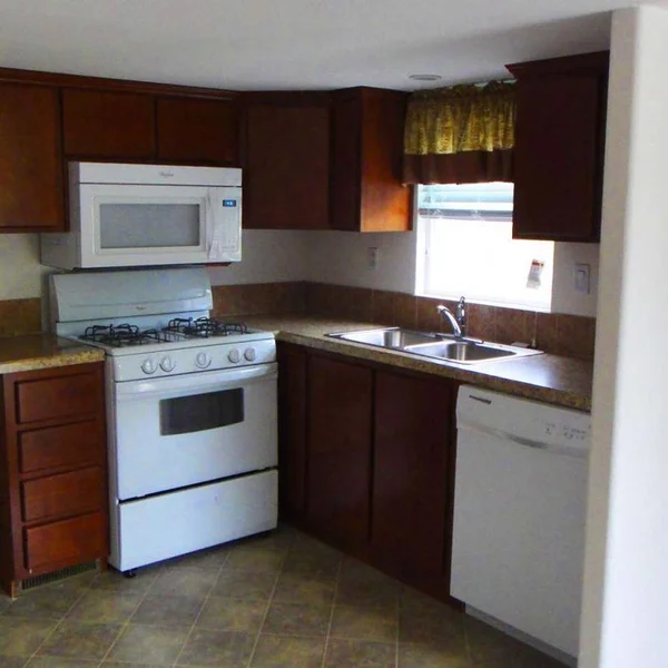 This manufactured home kitchen showcases classic wood cabinetry with modern appliances, providing a functional and stylish cooking space.