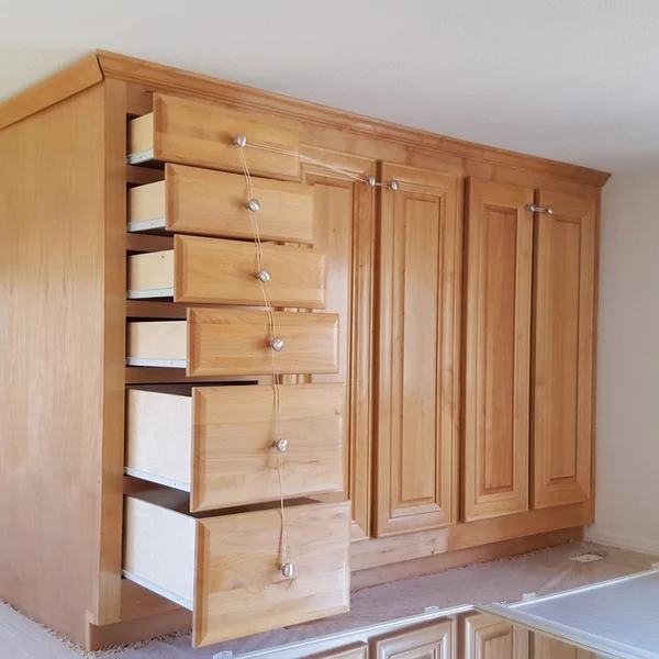 Light wood kitchen cabinets with silver hardware are shown in a manufactured home.