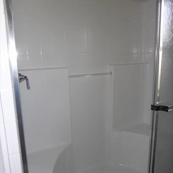 The shower in this ADU features bright white tiling and chrome fixtures for a clean, modern look.