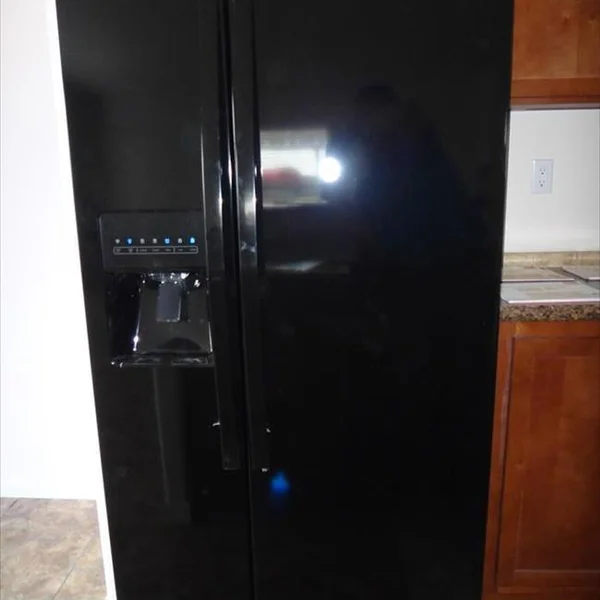 This sleek, black refrigerator with built-in water dispenser maximizes kitchen space in this new manufactured home.