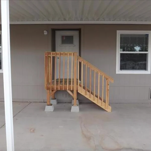 Custom-built wooden steps provide easy access to the entrance of this manufactured home, adding to its curb appeal.