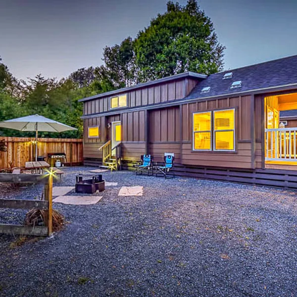 Brown modern ADU or park model features an outdoor patio, gravel landscaping, and inviting lighting.