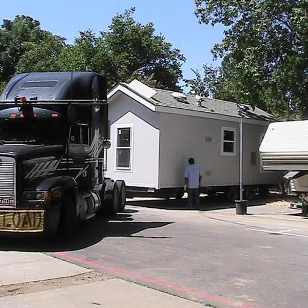 A manufactured home is transported by a semi-truck for ADU or student housing solutions.