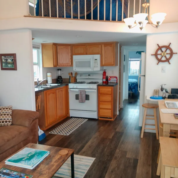 Nautical themed tiny home showcases a compact kitchen and living area with a charming loft space.