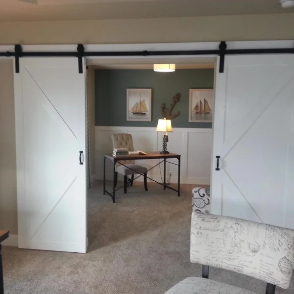 Barn doors open to a home office with nautical decor, creating an elegant space in a manufactured home or ADU.