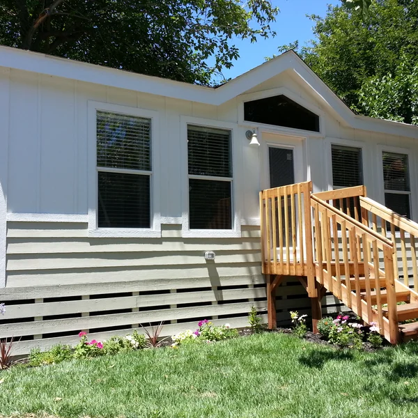 This stylish manufactured ADU showcases two-tone siding, custom wooden steps, and clean landscaping, perfect for an elegant backyard tiny home setup.