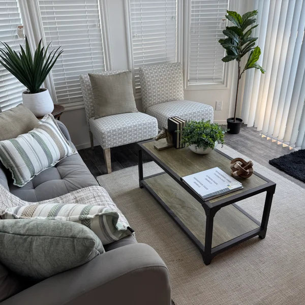 Bright living room features a gray sofa, patterned chairs, and coffee table for real estate staging.