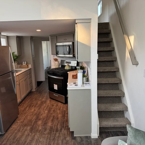 Cozy kitchen and staircase in a modern real estate property featuring gray cabinets and stainless steel appliances.
